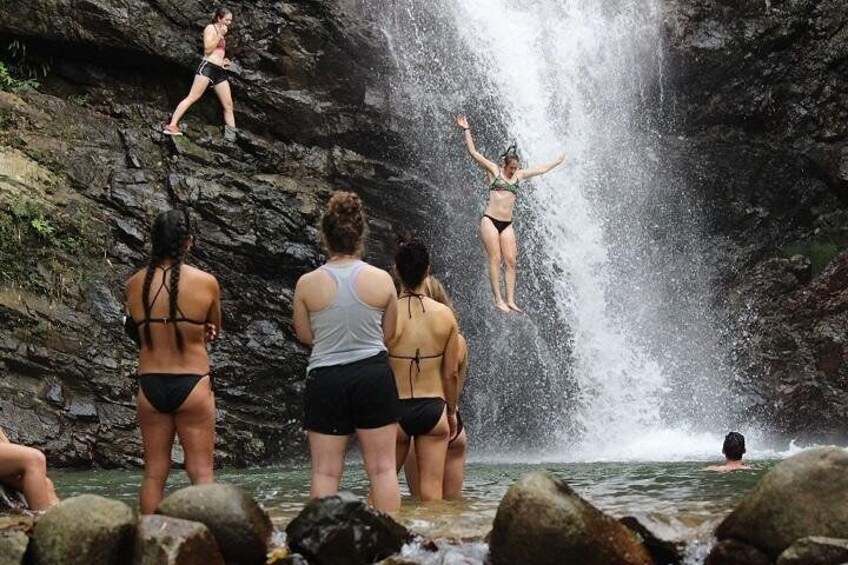 A group of people at a waterfall with some jumping into the water. 5