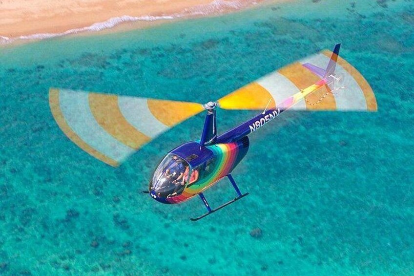 A colorful helicopter flying over a turquoise sea with a beach in the background. 3