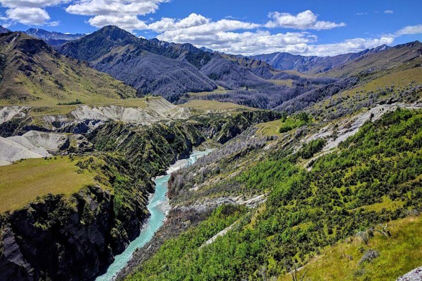 A river winding through a mountainous landscape with green vegetation and rocky terrain. 3
