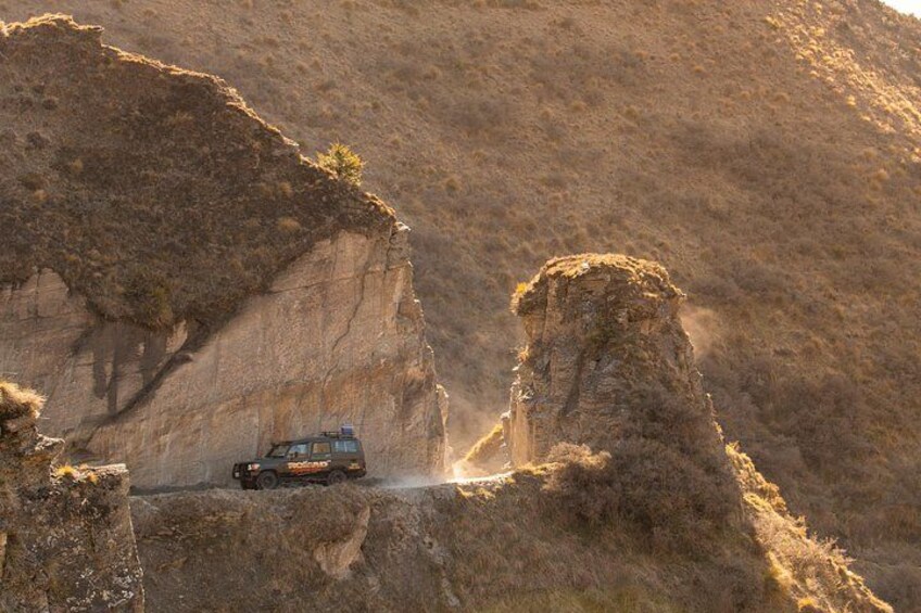 A vehicle navigating a narrow, rocky canyon with steep cliffs. 2