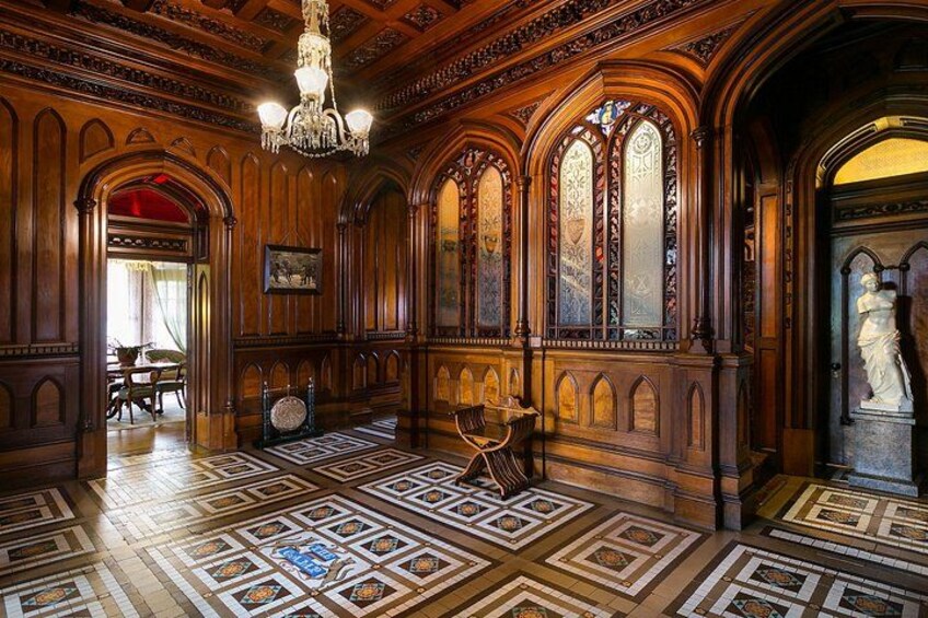 Una habitación ornamentada con paneles de madera, un candelabro y baldosas de suelo con diseños. 3