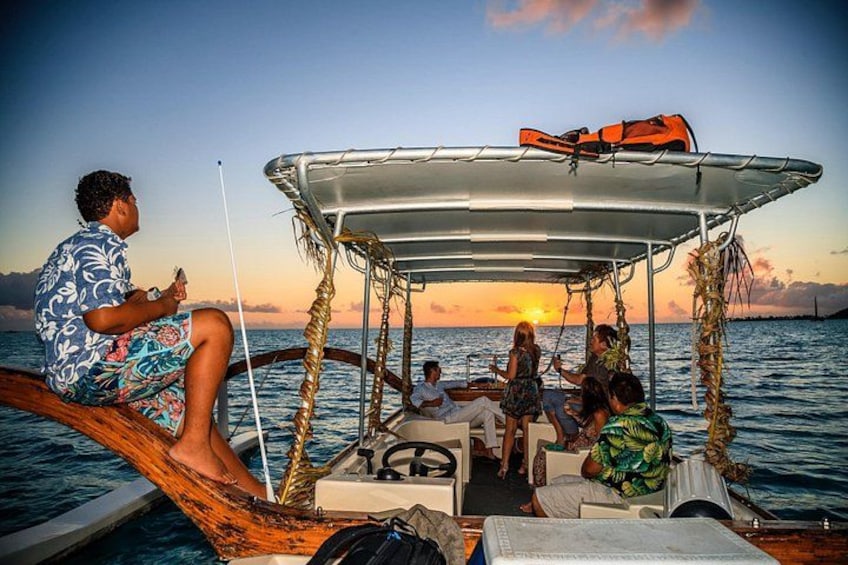 Eine Gruppe von Menschen auf einem Boot mit einem Sonnensegel, Angelruten und einem Sonnenuntergang im Hintergrund. 3