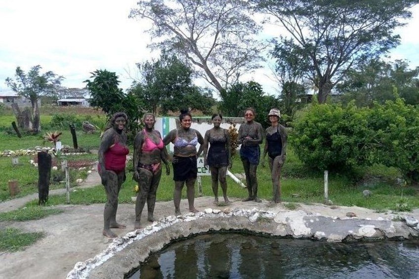 Un grupo de personas de pie junto a un estanque pequeño en un entorno natural, con árboles y una cerca al fondo. 3