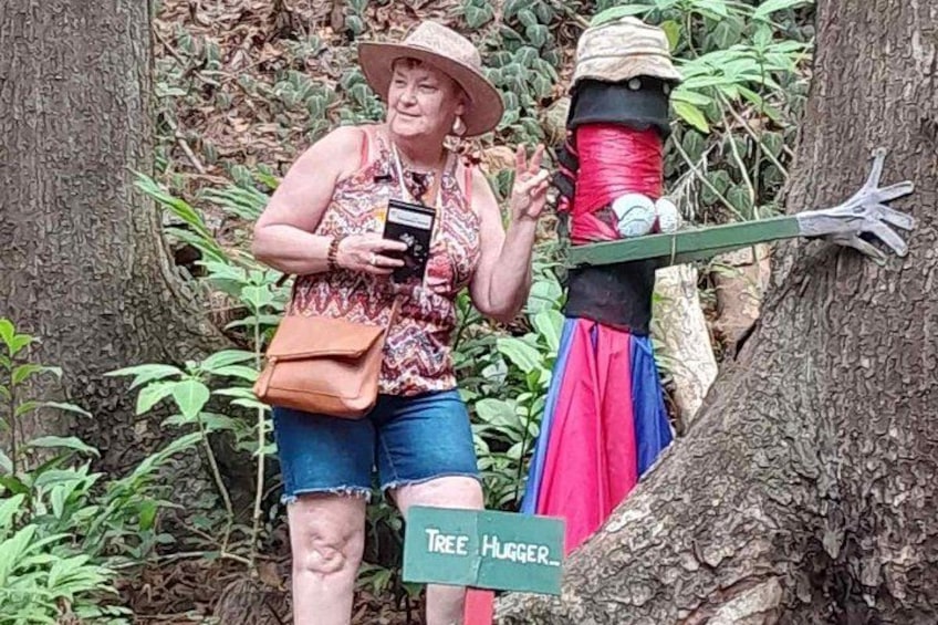Una persona de pie junto a un árbol con un cartel que dice 'Tree Hugger'. 4