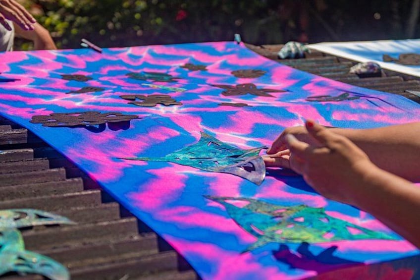 A colorful fabric with a pattern, possibly a tablecloth or blanket, with a person handling a piece of it. 3