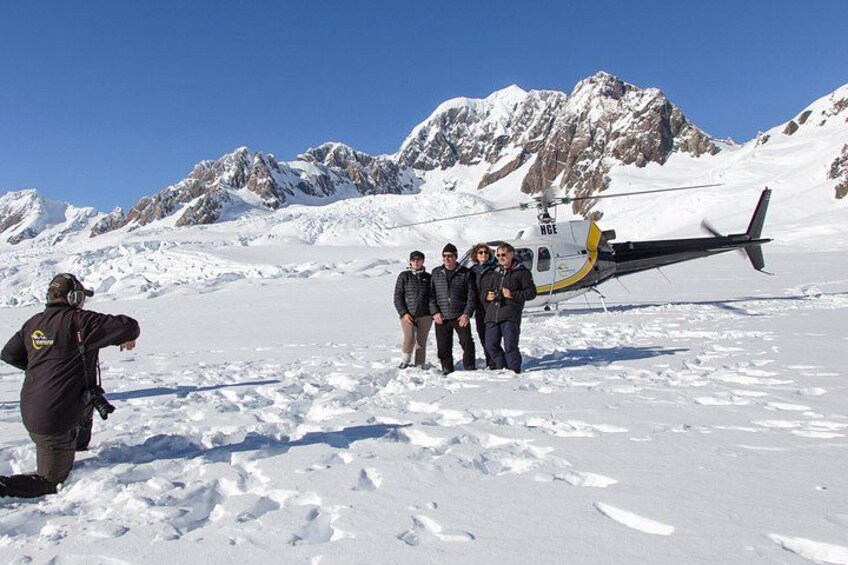A group of people standing on snow-covered ground with a helicopter in the background. 5