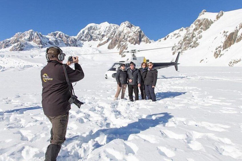 A group of people standing on snow-covered ground with a helicopter in the background. 4