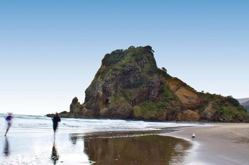 A rocky coastline with waves crashing onto the shore and a person walking along the beach. 5