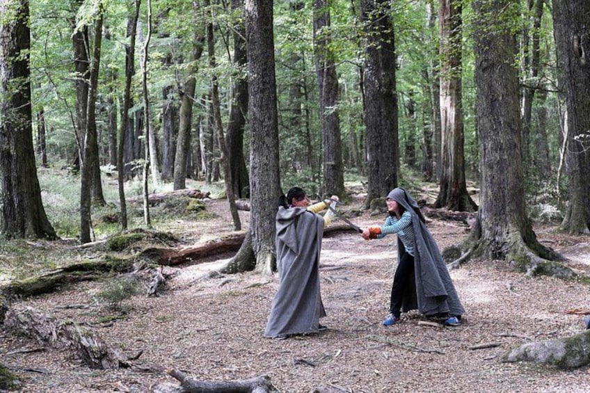 Two people in a forest, one holding a bat and the other holding a ball. 4