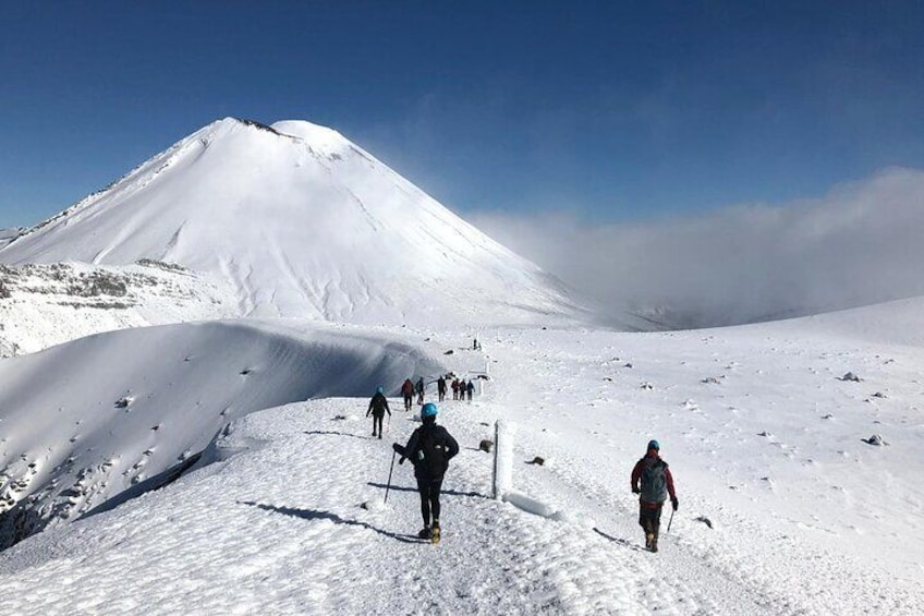 Un paysage de montagne enneigé où l’on voit un groupe de personnes en randonnée. 3