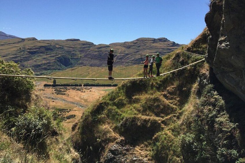 A rope bridge over a valley with hikers on it. 3