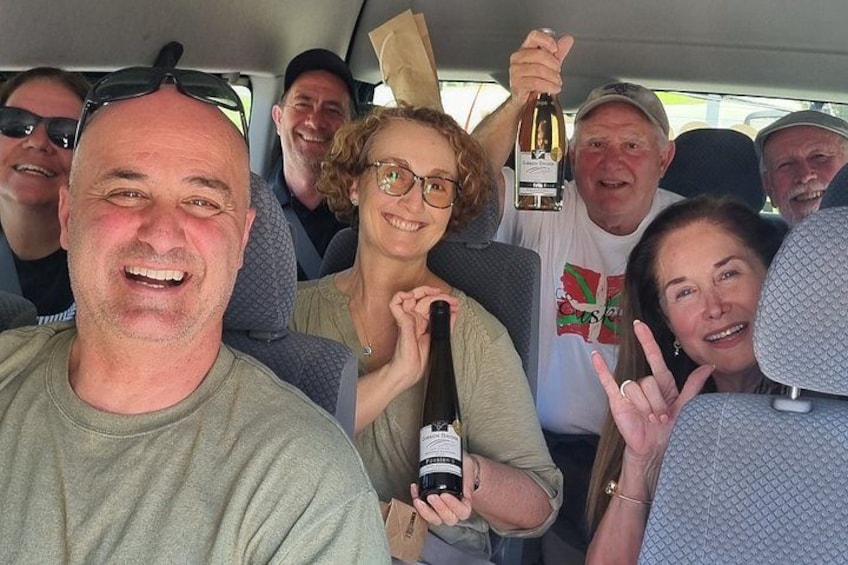 A group of people in a vehicle, some holding a bottle. 2