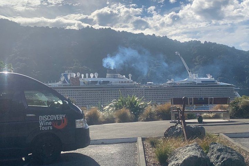 A cruise ship with smoke visible, a van labeled 'Discovery Wine Tours,' and a mountainous landscape in the background. 4