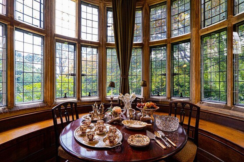 A dining table set with plates, silverware, and a vase of flowers in a room with large windows. 5