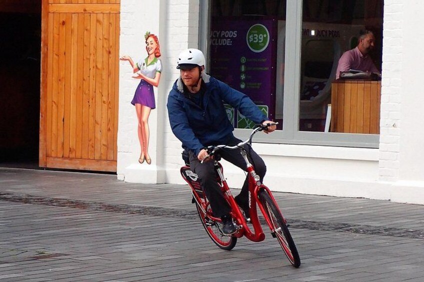 A person riding a red bicycle on a wooden boardwalk. 4