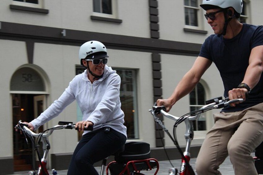 Two people riding bicycles on a street. 5