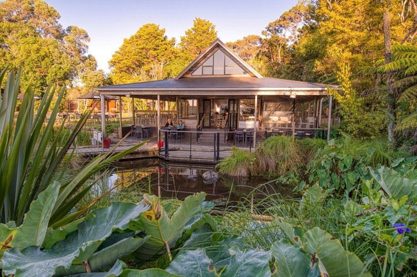 A house with a covered patio overlooking a pond, surrounded by lush greenery. 2