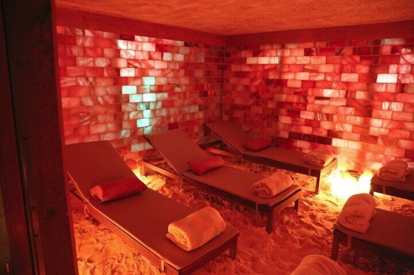 A sauna with three wooden loungers, a brick wall, and a visible fire. 5