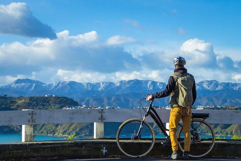 Eine Person steht neben einem Fahrrad, im Hintergrund eine Berglandschaft. 4
