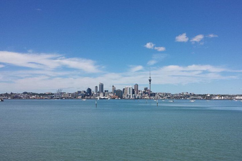 A coastal city skyline with a prominent tower, calm waters, and a clear sky. 3