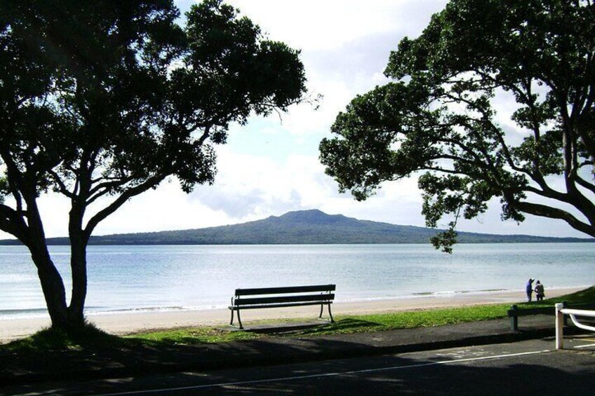 A bench by a lake with trees and a distant mountain. 2