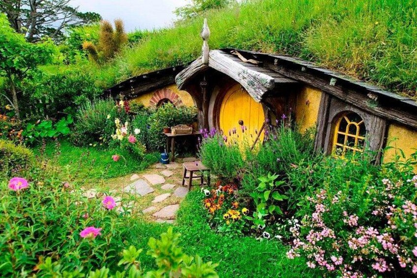 Ein hobbitähnliches Haus, umgeben von üppigem Grün und Blumen. 3