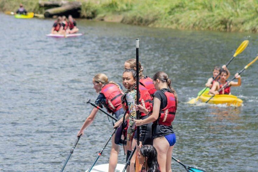 People kayaking on a river, wearing life jackets. 4