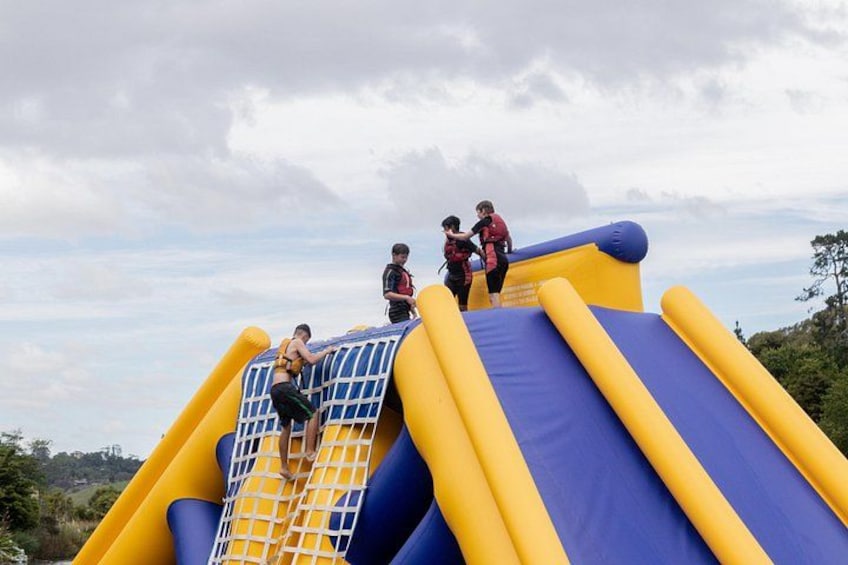 Un tobogán inflable grande con una sección de red, sobre un cielo nublado. 1