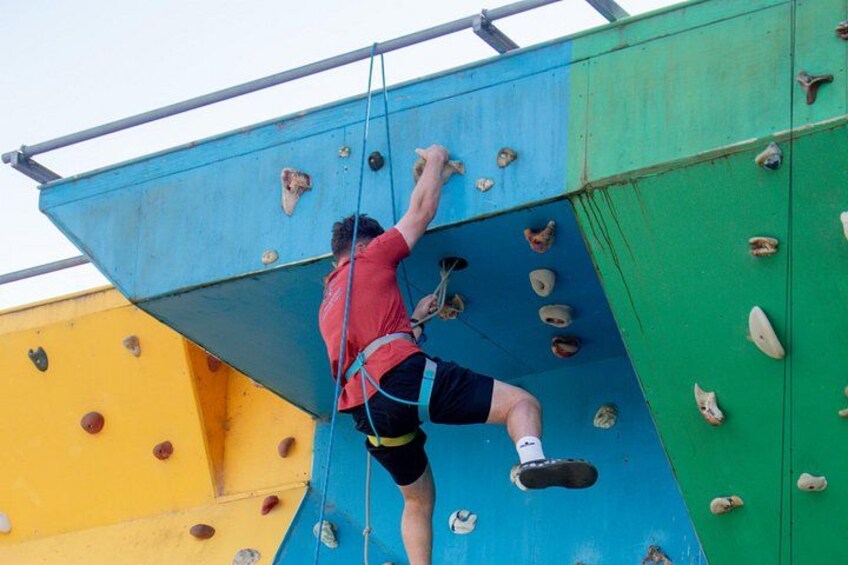 Una persona escalando una pared de escalada multicolora con puntos de agarre. 4