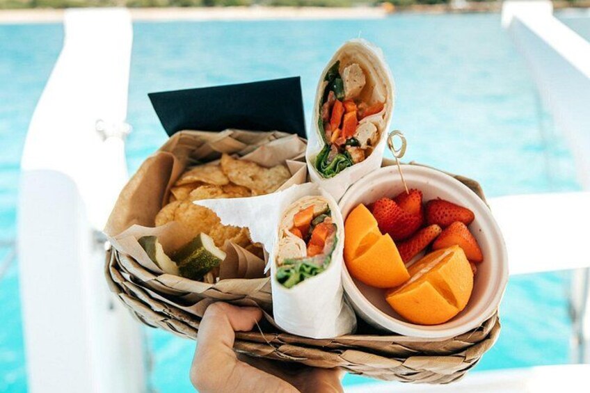 En korg med wraps och frukt bredvid en pool. 2