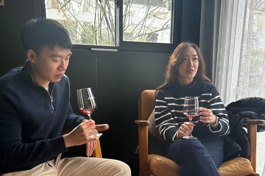 Two people sitting on chairs, each holding a wine glass. 5