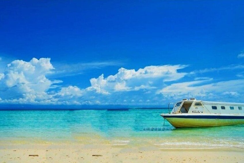 En båd på en strand med klart turkis vand og en blå himmel. 5