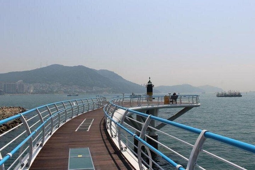 Una passerella in legno con ringhiere blu che conduce a un faro. 1