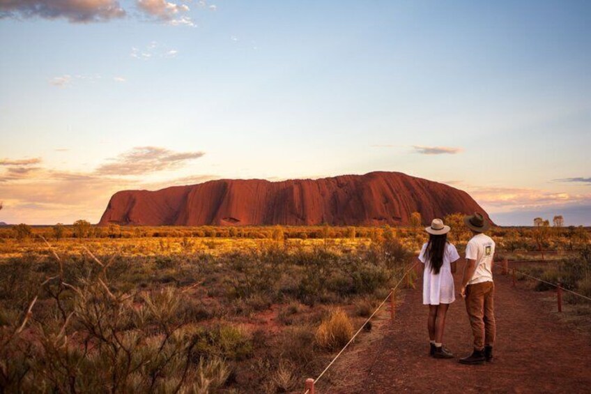 A large red rock formation, a clear sky, and a person in a white shirt and hat. 4