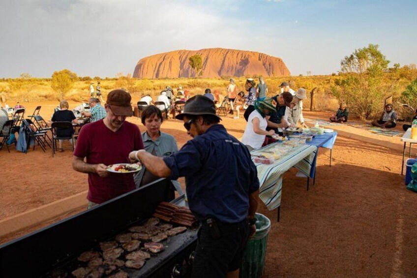 A group of people dining outdoors with a large rock formation in the background. 5