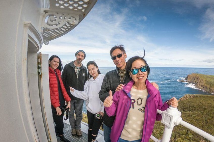 A group of people standing on a platform with a scenic ocean view. 1