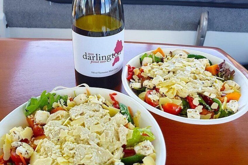 Two bowls of salad with a bottle of wine on a table. 3
