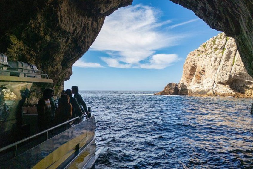A boat with people on a rocky coastline, a clear sky, and calm sea. 3