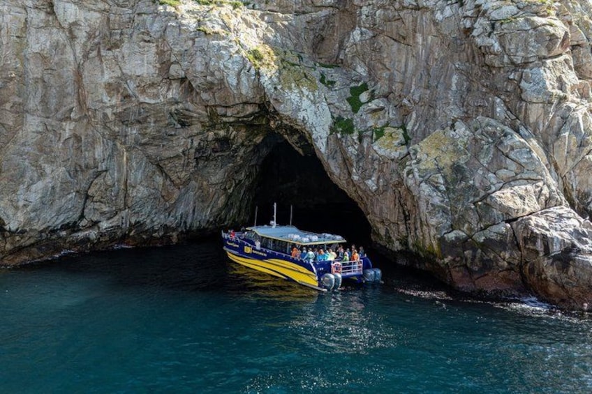A boat with passengers entering a rocky cave. 1
