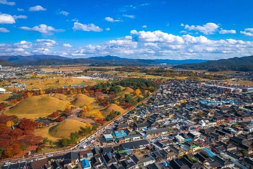 An aerial view of a residential area with houses, roads, and rolling hills in the background. 2