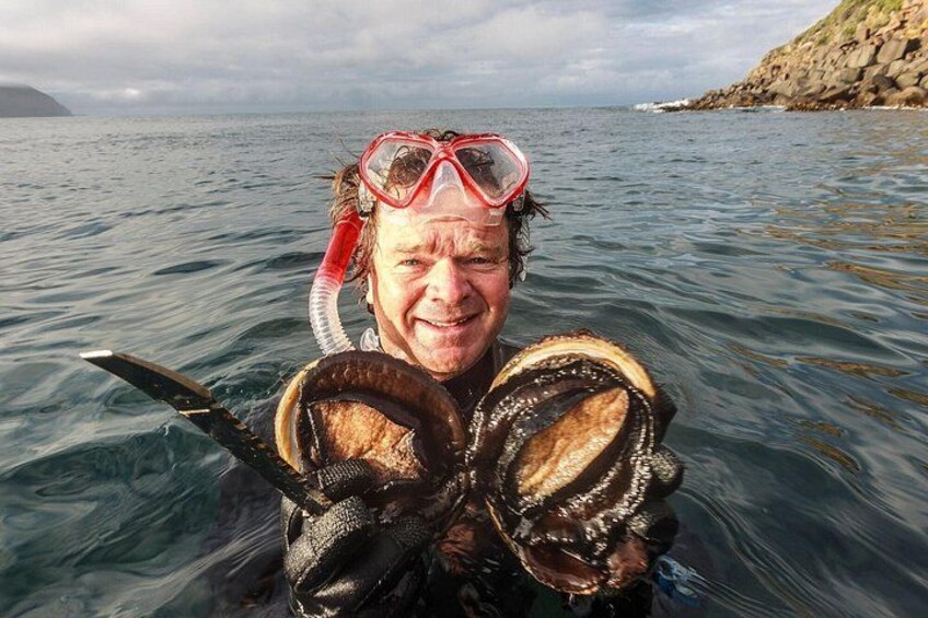 Eine Person hält eine große Muschel im Meer. 5