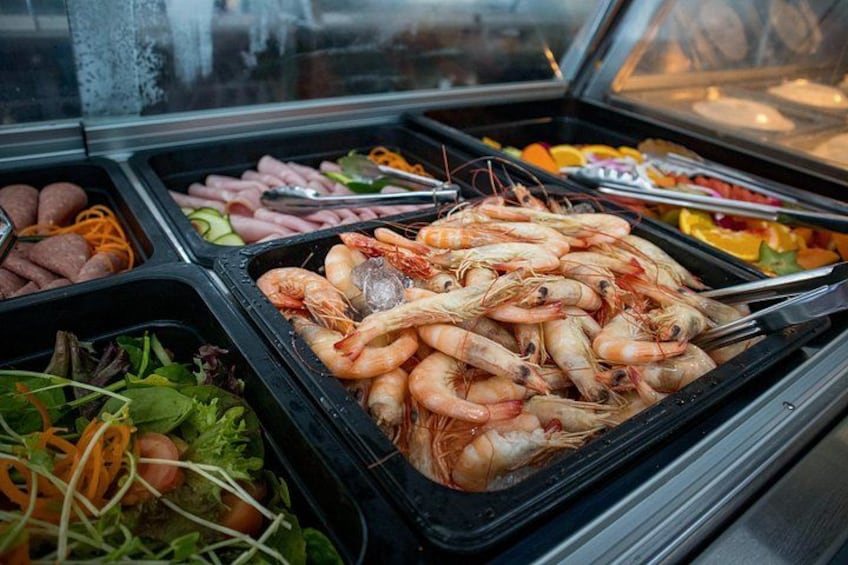 En buffet med forskellige retter, herunder rejer, grøntsager og kød. 4