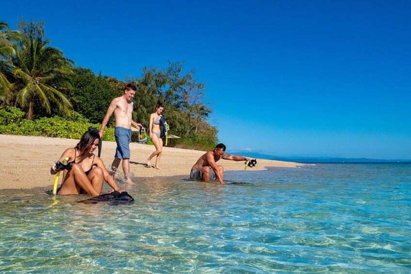 Mensen op een strand met helder water, palmbomen en een heldere lucht. 4