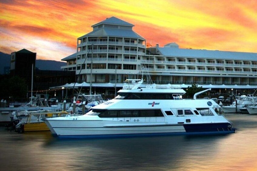 A large white yacht docked at a marina with a building in the background. 1