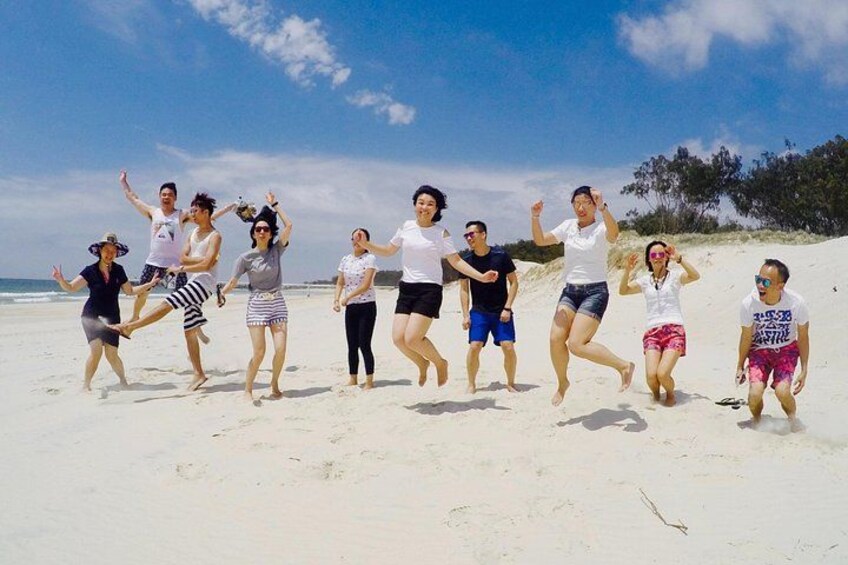 En gruppe mennesker danser på en sandstrand under en klar himmel. 3