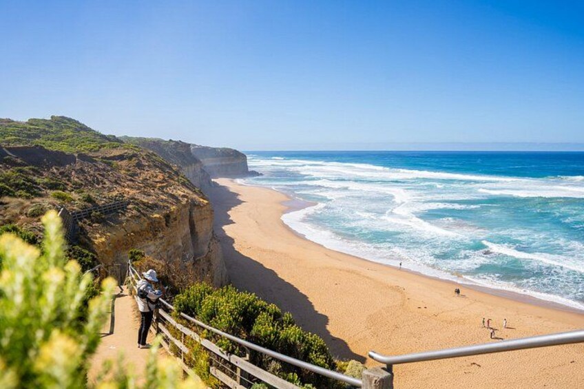 A coastal landscape with a sandy beach, cliffs, and a clear blue sky. 3