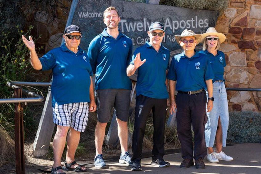 A group of people in blue shirts standing in front of a sign that reads 'Welcome to Twelve Apostles.' 2