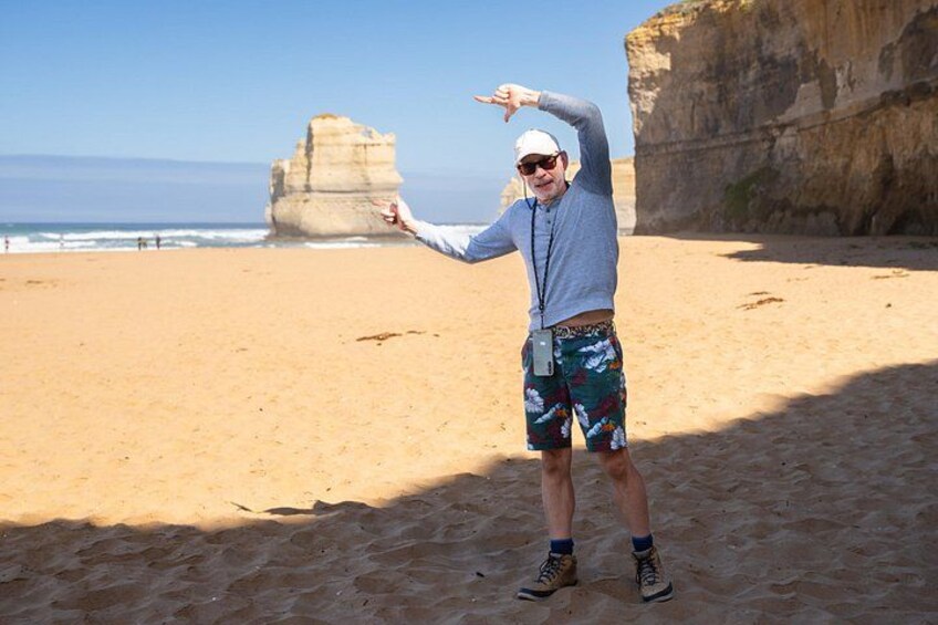 A person standing on a sandy beach with a large rock formation in the background. 2