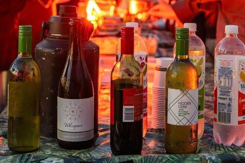 A variety of bottles, including wine and water, on a table with a patterned tablecloth. 3
