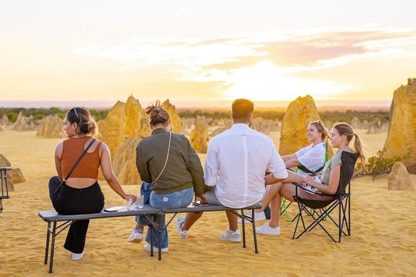 A group of people sitting on a metal table outdoors with a desert landscape in the background. 5